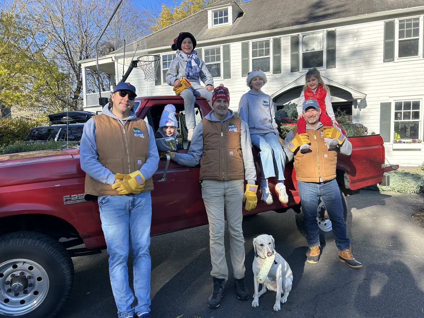 The Winterwood Trees team, their children and dog beside the red delivery truck